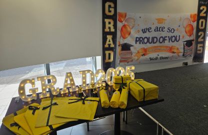 Graduation banner displayed above a table adorned with yellow and black decorations and items for the celebration.