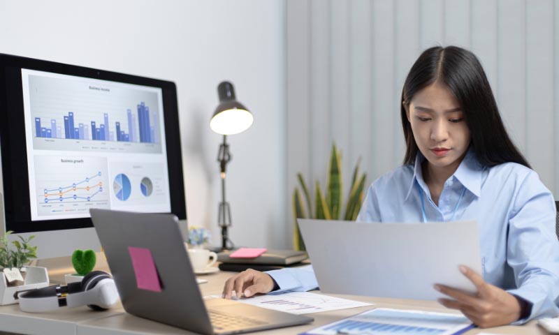 A woman reviewing documents at a computer